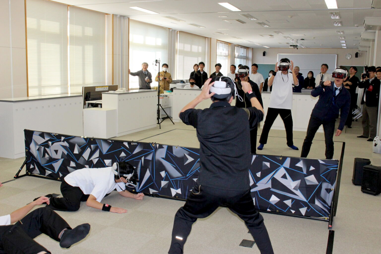 HADO体験会でARゴーグルとアームセンサーを装着し、教室で回避・攻防する参加者と観客の様子（新庄神室産業高校）