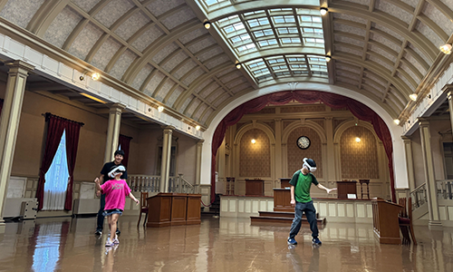 HADO体験会でARゴーグルとアームセンサーを装着し、教室で回避・攻防する参加者と観客の様子（新庄神室産業高校）