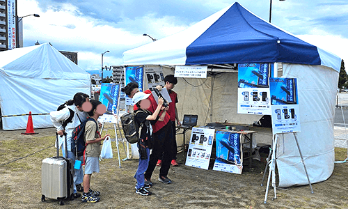 フルーツEXPO前夜祭の会場で、AR水族館の体験ブースに来場者が集まっている様子