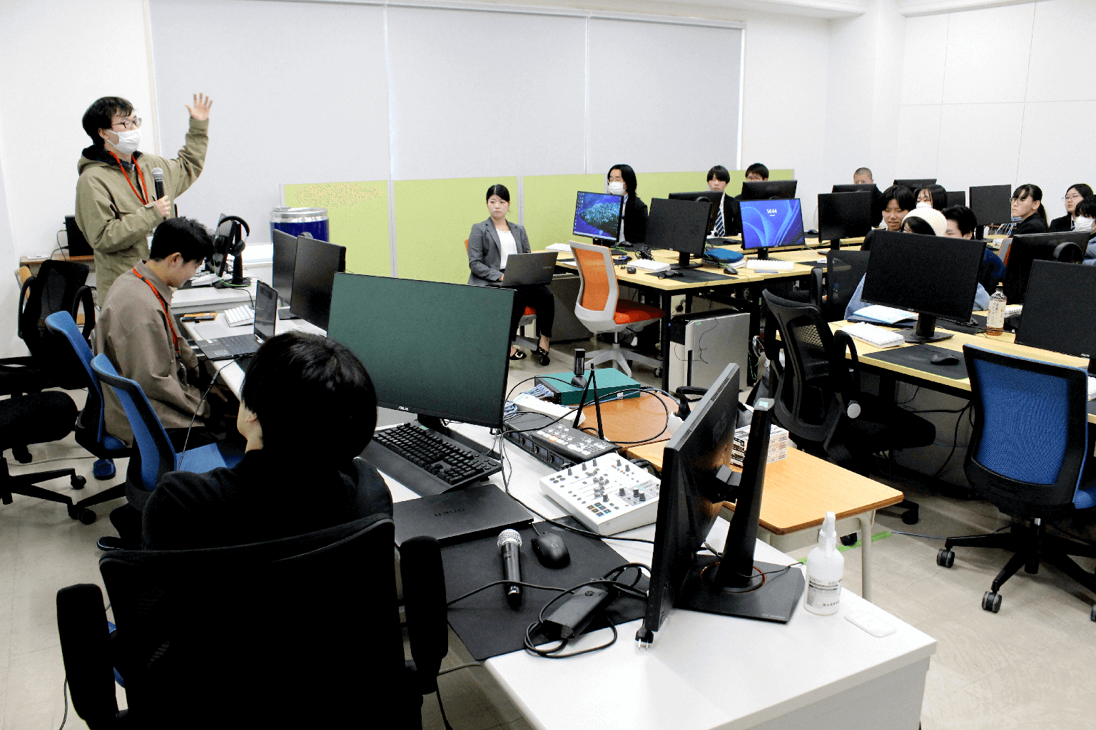 パソコン室で、運営スタッフが参加者にイベント内容を説明している様子