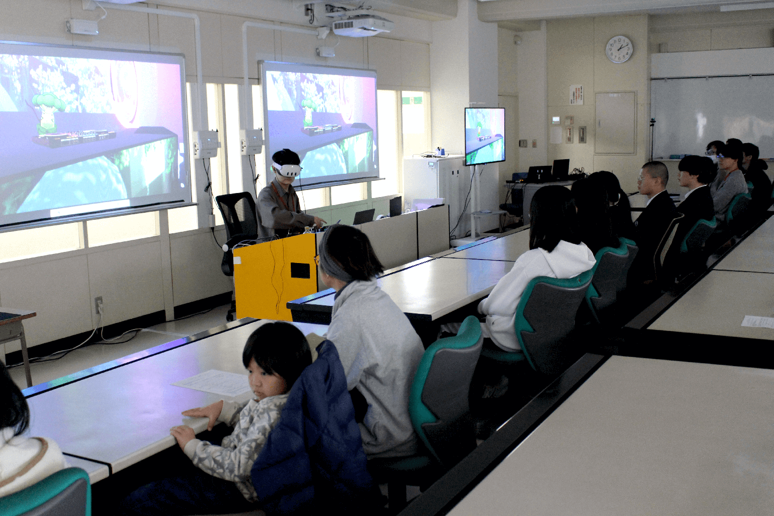 オープニングイベントで、VR機器を使ったデモの様子をスクリーンに投影している様子