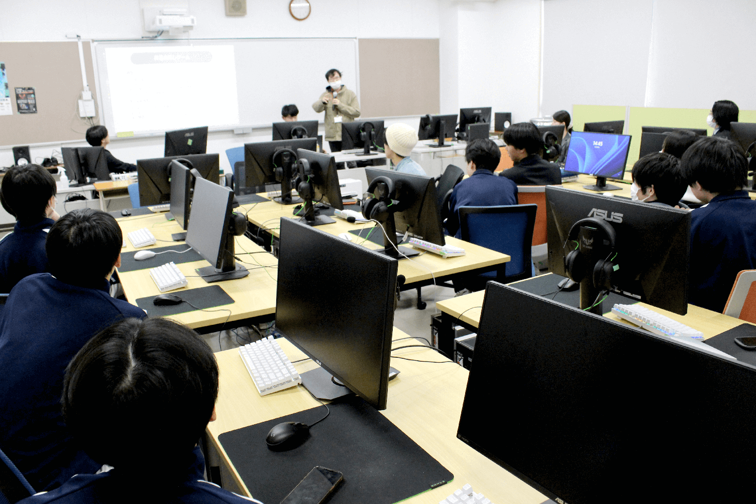 最終日の審査・発表会で、会場全体に向けて進行説明を行っている様子